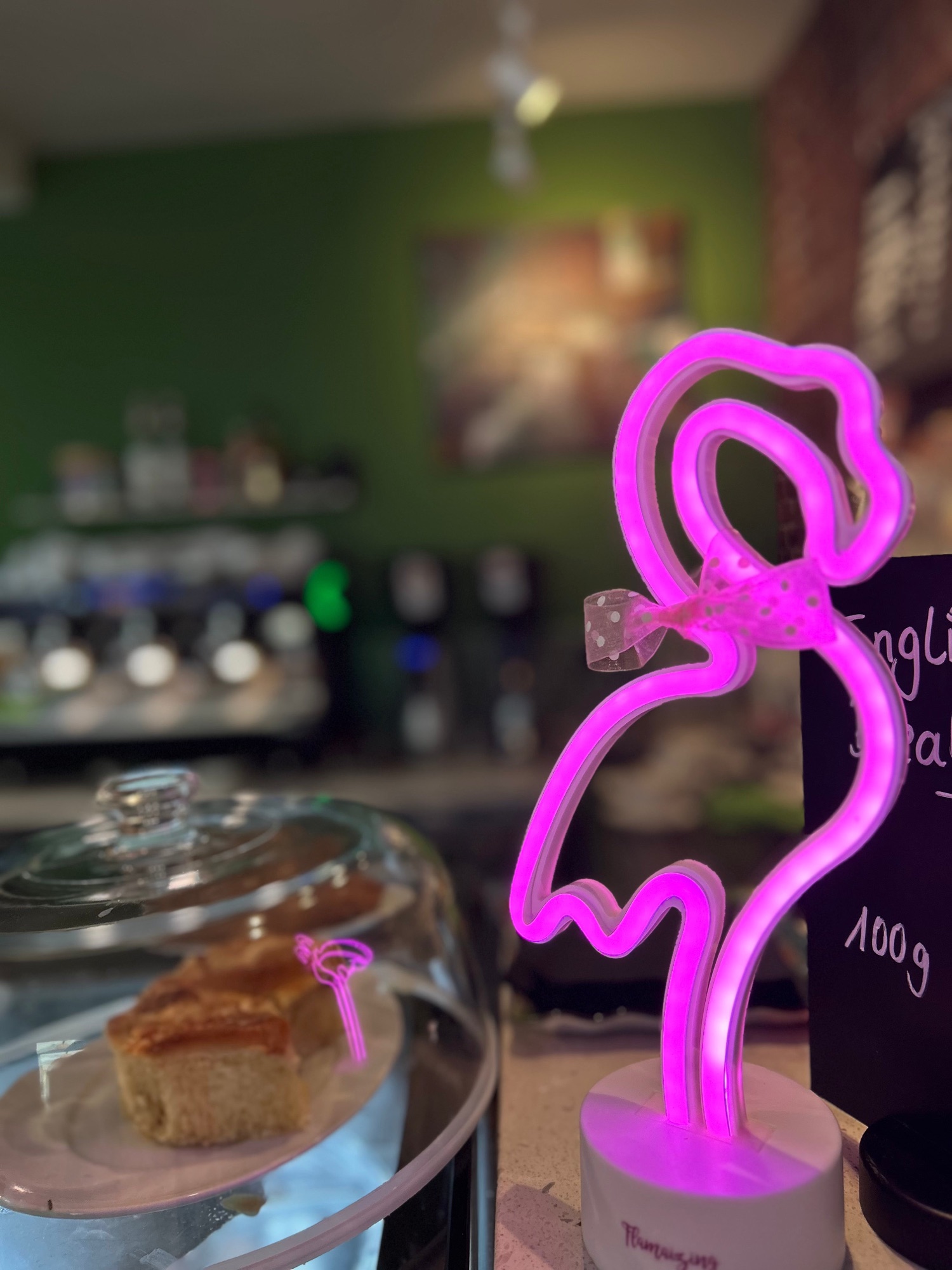 Pinke Neon-Flamingo-Lampe auf dem Tresen neben der Kuchenglocke