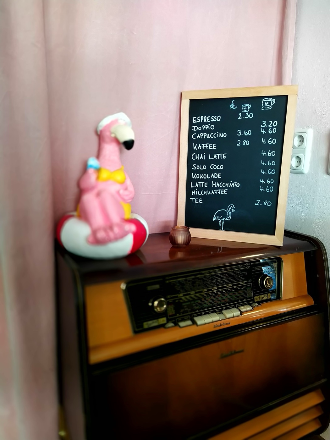 Flamingo-Figur mit Schwimmring neben der Kreidetafel auf dem Vintage-Radio