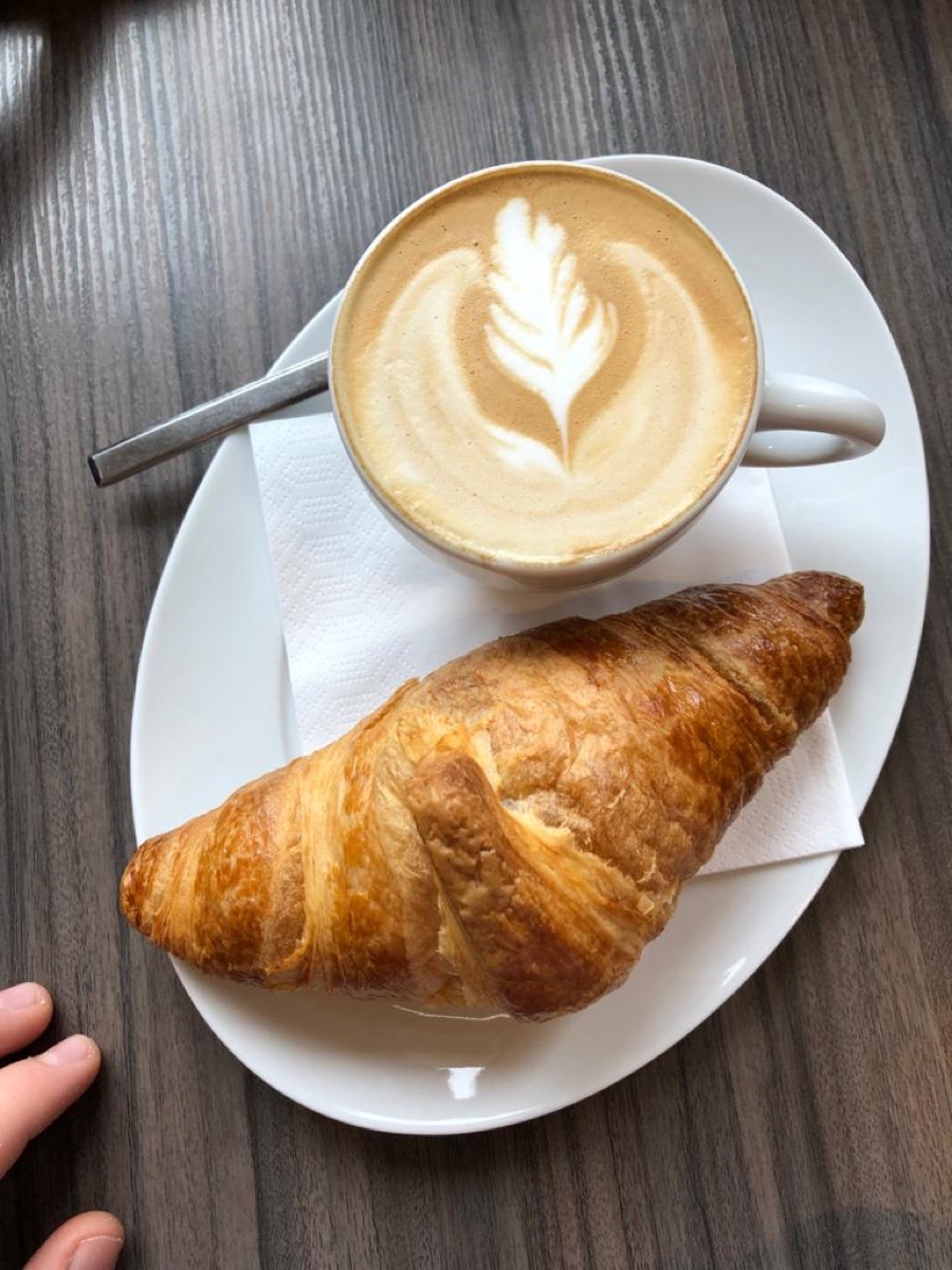 Cappuccino mit Latte-Art und Buttercroissant von oben