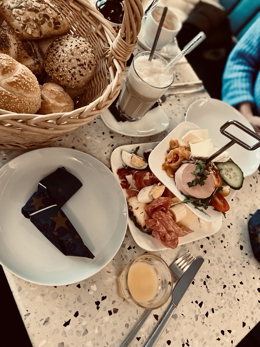 Frühstückstisch von oben — Semmelkorb, Latte macchiato und belegte Teller
